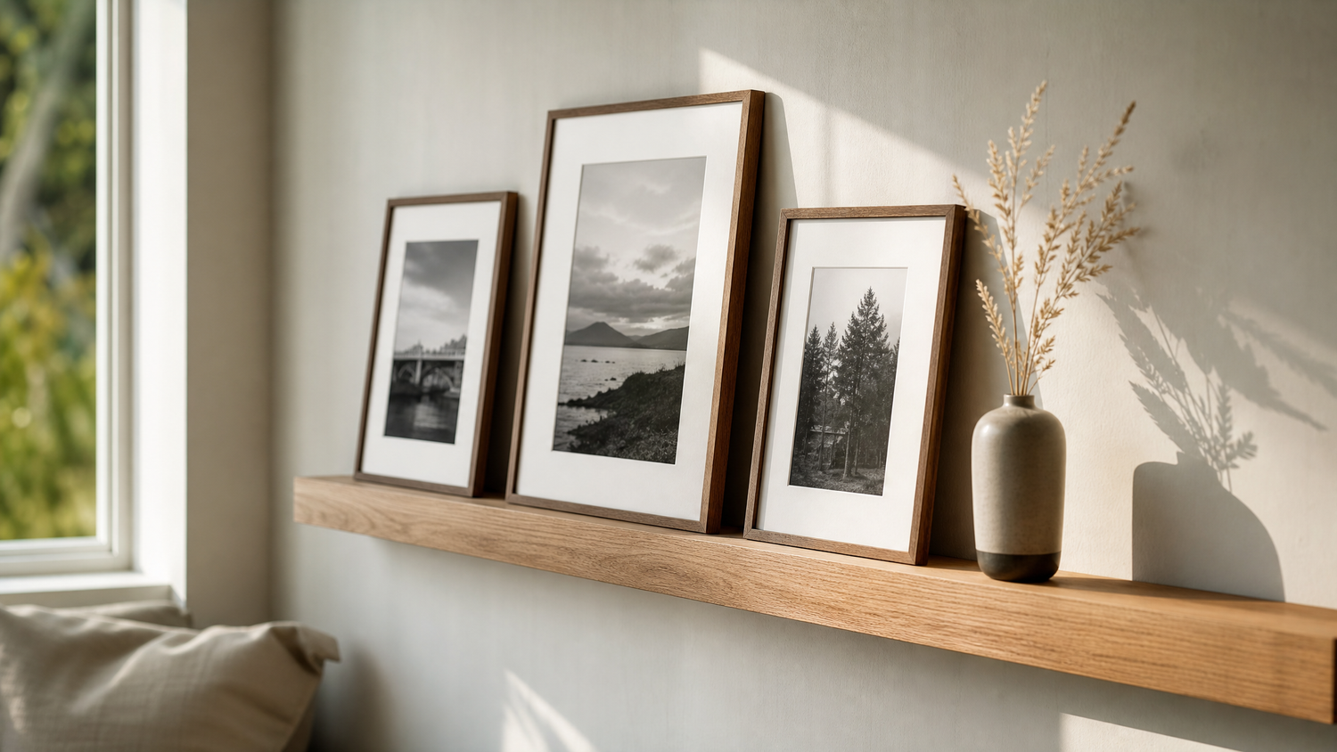 Bilderleiste aus Eichenholz mit drei gerahmten Fotografien an einer hellen Wand