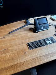 Blick von oben auf die geölte Wildeiche-Platte mit Tastatur und Telefon